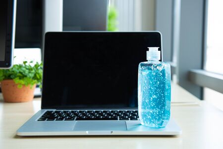 blue alcohol gel bottle for use in hand washing placed on laptop in workplace with headphone, prevent germs protect from coronavirus or covid-19 virus world pandemic,health care and medicine conceptの写真素材