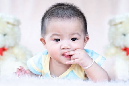 Closeup asian baby infant laying comfortably on bed playing with bear doll on softness cushion,Baby development concept.の写真素材