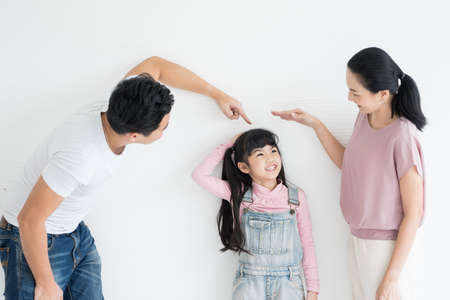 Education concept.Portrait enjoy happy smiling love asian family father and mother with little asian girl learning and writing in book with pen making homework at home.の写真素材