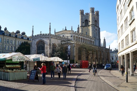 CAMBRIDGE, UK - FEBRUARY 16 2016: Pedestrians and a cyclist pass through Market Square in Cambridge, England, with Great St Mary's Church in the background.のeditorial素材