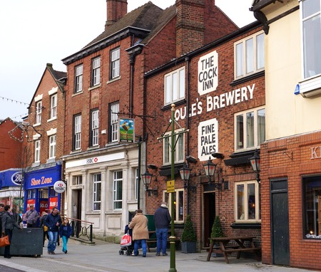 LEEK, UK - DECEMBER 31 2015: Pedestrians walk past a pub, bank and shops along Derby Street, the main shopping area in the historic market town of Leek, in the Staffordshire Moorlands, England.のeditorial素材