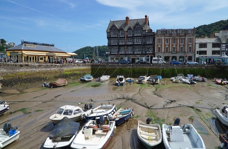 DARTMOUTH, UK - JULY 6 2016: Crowds throng the South Embankment harbour promenade in the coastal riverside town of Dartmouth, Devon. Several small boats sit in a sheltered harbour area, at low tide.のeditorial素材