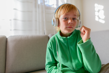 Handsome boy listening to music and sitting on sofa at homeの写真素材