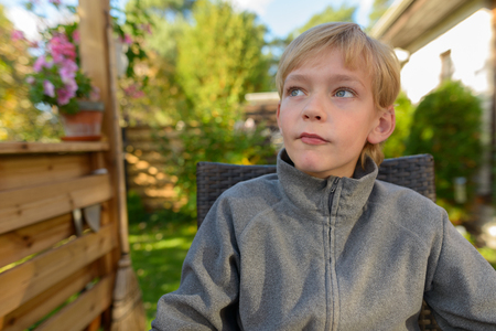 Handsome boy sitting and thinking in the backyard at homeの写真素材