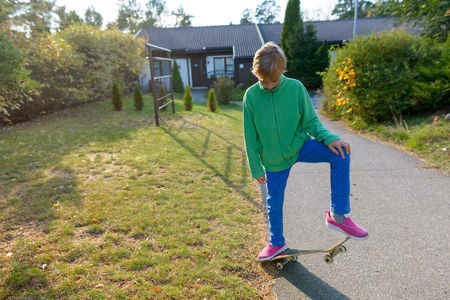 Handsome boy playing with skateboard in the front yard at homeの写真素材