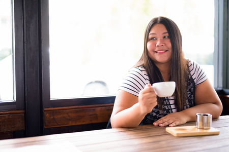 Beautiful overweight Asian woman relaxing at the coffee shopの写真素材