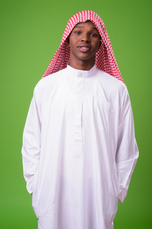 Young African man wearing traditional Muslim clothes against greの写真素材
