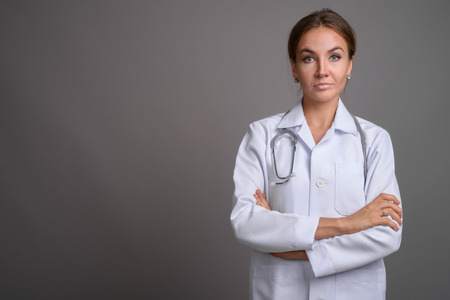 Young beautiful woman doctor against gray backgroundの写真素材