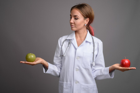 Young beautiful woman doctor against gray backgroundの写真素材