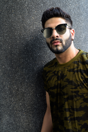 Young handsome Indian man thinking while wearing sunglasses agaiの写真素材