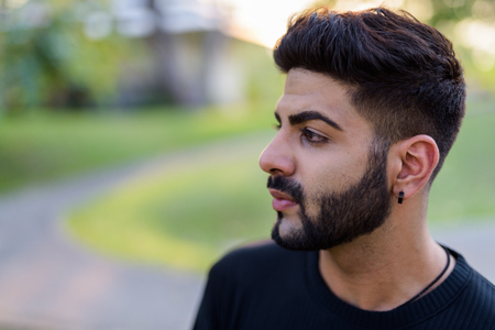 Close up profile view of young handsome Indian man thinking at tの写真素材