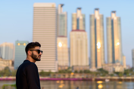 Profile view of young handsome Indian man thinking while wearingの写真素材