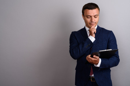 Businessman wearing suit against gray backgroundの写真素材