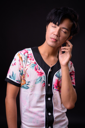 Young handsome Asian man against black backgroundの写真素材