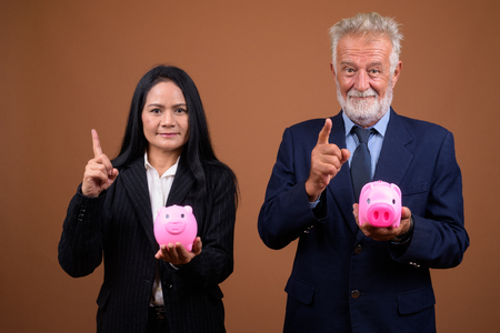 Mature multi-ethnic business couple against brown backgroundの写真素材