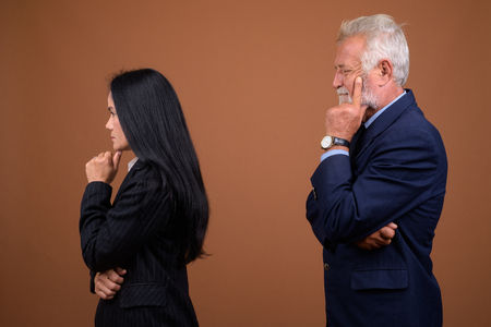 Mature multi-ethnic business couple against brown backgroundの写真素材