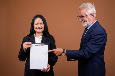 Mature multi-ethnic business couple against brown backgroundの写真素材