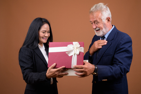 Mature multi-ethnic business couple against brown backgroundの写真素材