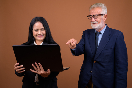 Mature multi-ethnic business couple against brown backgroundの写真素材