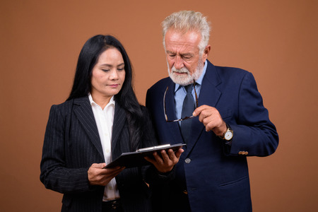 Mature multi-ethnic business couple against brown backgroundの写真素材