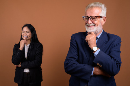 Mature multi-ethnic business couple against brown backgroundの写真素材