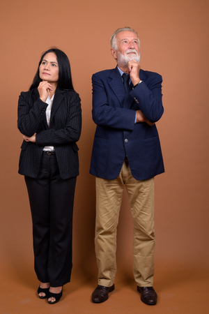 Mature multi-ethnic business couple against brown backgroundの写真素材