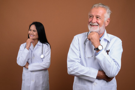 Mature multi-ethnic couple doctors against brown backgroundの写真素材