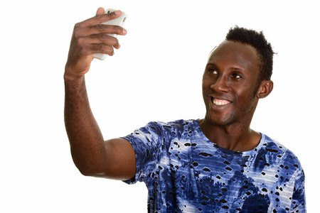 Young happy black African man smiling while taking selfie with mの写真素材
