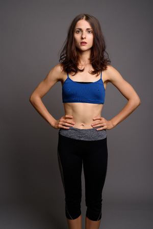 Young beautiful woman ready for gym against gray backgroundの写真素材
