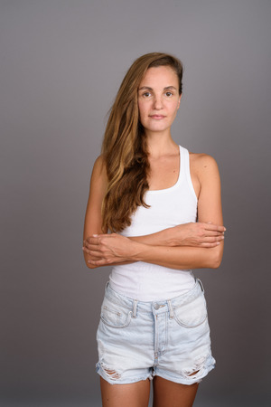 Young beautiful woman with long blond hair against gray backgrouの写真素材