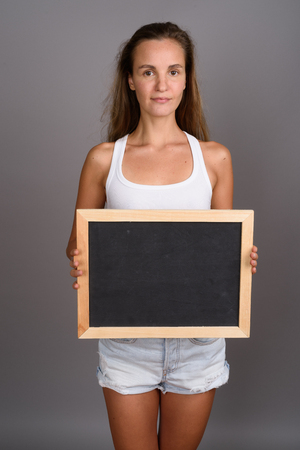 Young beautiful woman with long blond hair against gray backgrouの写真素材