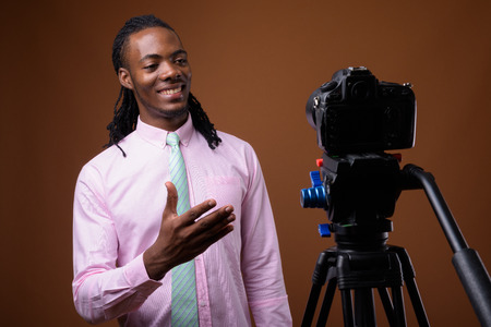 Young handsome African businessman against brown background