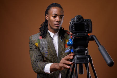 Young handsome African businessman against brown background
