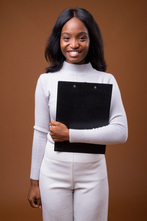 Young beautiful African Zulu businesswoman against brown backgroの写真素材