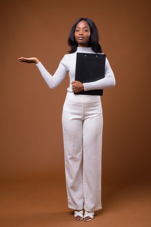 Young beautiful African Zulu businesswoman against brown backgroの写真素材