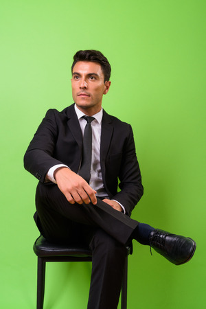 Young handsome Hispanic businessman against green backgroundの写真素材