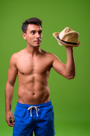 Young handsome Hispanic man shirtless against green backgroundの写真素材