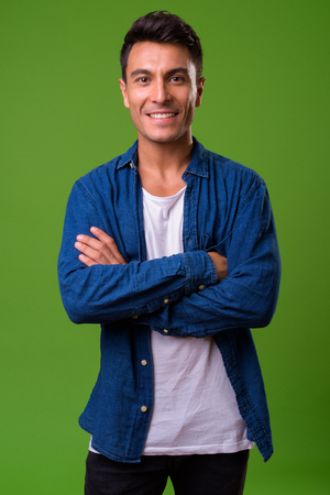 Young handsome Hispanic man against green backgroundの写真素材