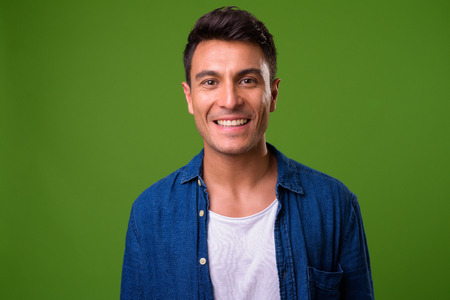 Young handsome Hispanic man against green backgroundの写真素材
