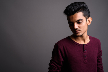 Young Indian man against gray backgroundの写真素材