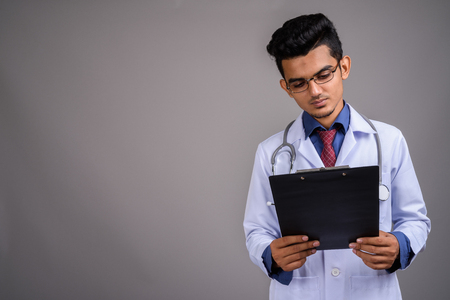 Young Indian man doctor against gray backgroundの写真素材