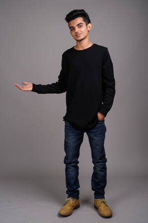 Young Indian man against gray backgroundの写真素材