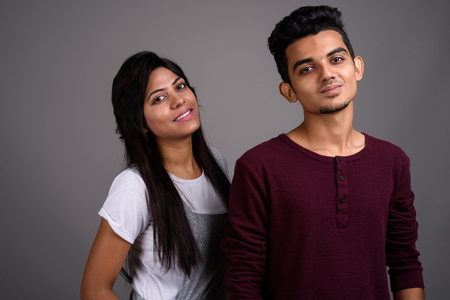Young Indian man and young Indian woman together against gray baの写真素材