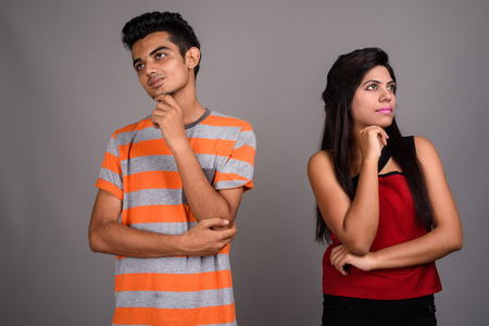 Young Indian man and young Indian woman together against gray baの写真素材