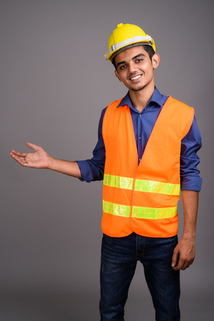 Young Indian man construction worker against gray backgroundの写真素材