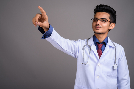 Young Indian man doctor against gray backgroundの写真素材