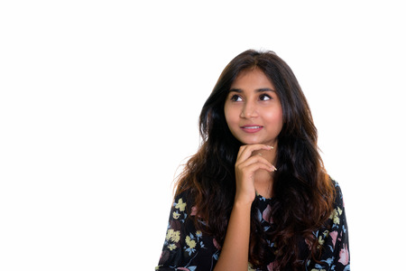 Studio shot of young happy Persian woman smiling and thinking whの写真素材