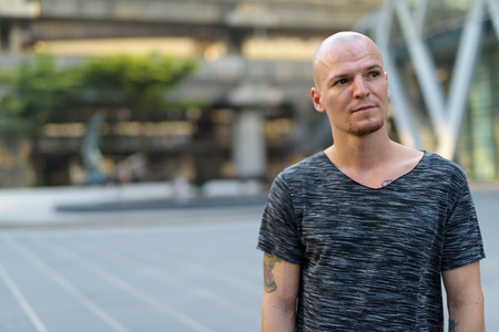 Young handsome bald man thinking against view of the mall and skの写真素材