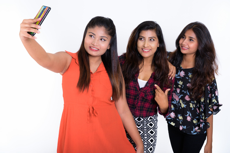 Studio shot of three happy young Persian woman friends smiling wの写真素材