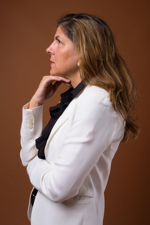Mature beautiful businesswoman against brown backgroundの写真素材